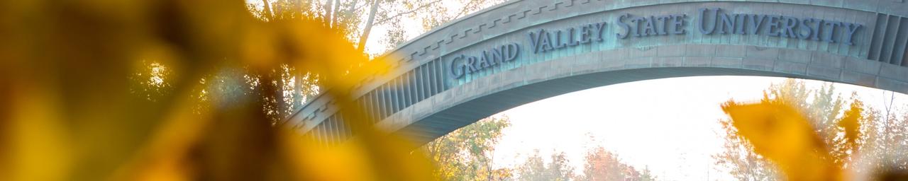 A look at the GVSU welcome bridge at the entrance of campus through fall leaves